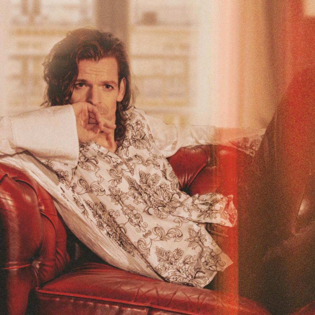 Maurice Monet, Promotiefoto van Maurice Monet op een rode bank - licht wazige fotosfeer