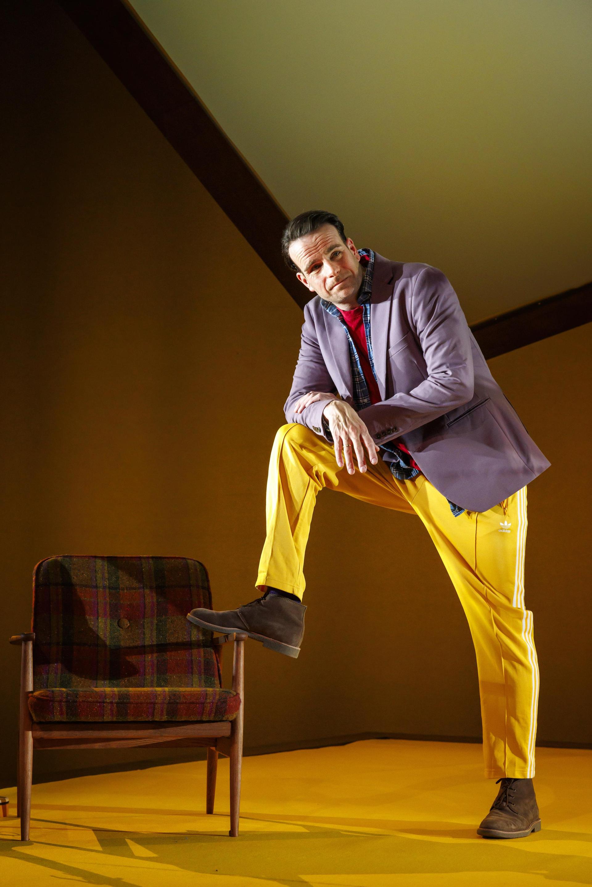 Scenefoto's van Henry van Loon op het podium met gele broek, rood shirt en jasje