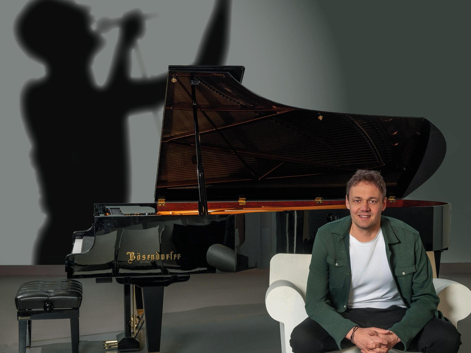 Bernd speelt Freddie Mercury, Promotiefoto Bernd van de Bos op een stoel voor een vleugel waarachter een schaduw zingt