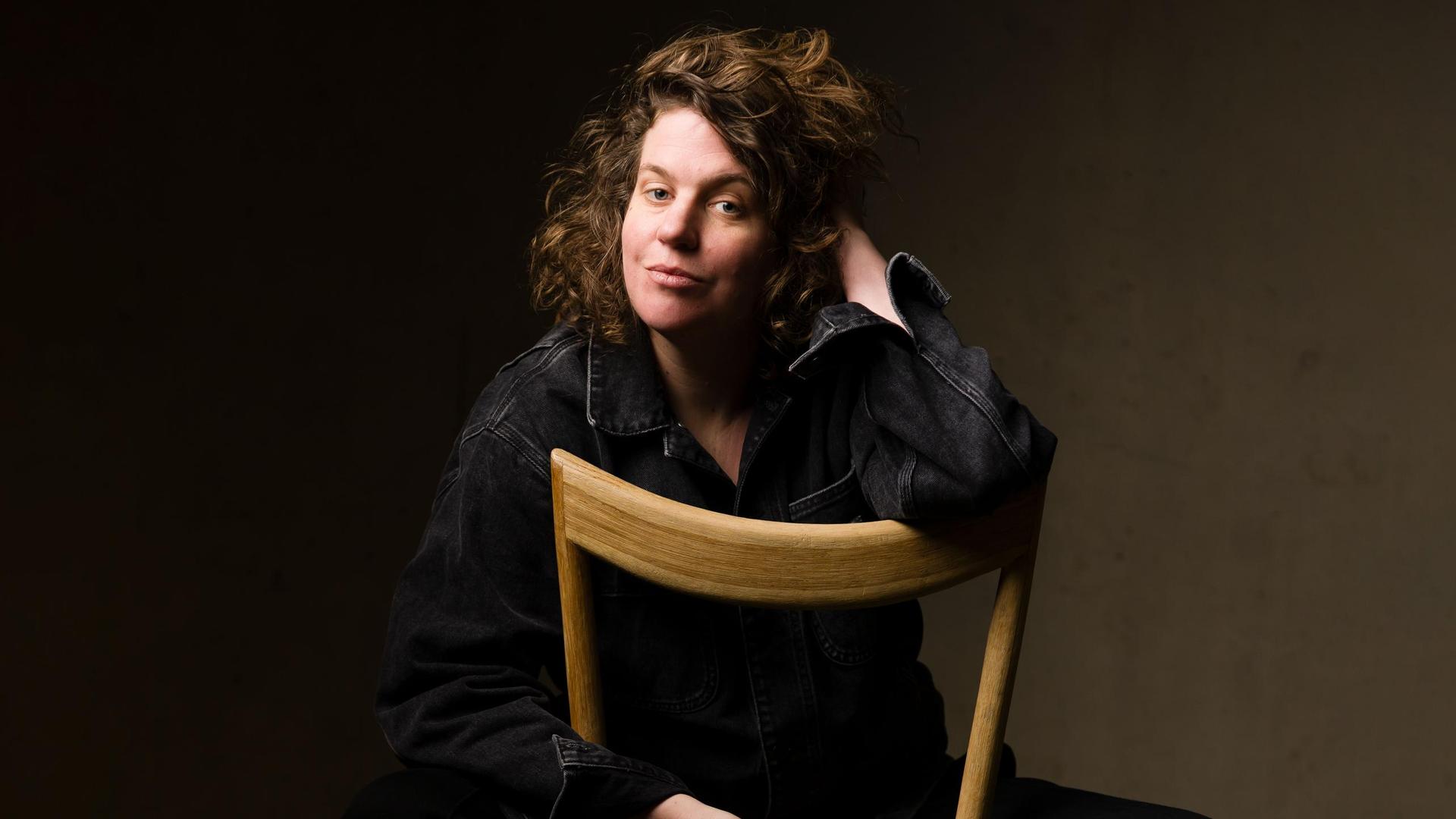 Kim Schuddeboom, Promotiefoto van Kim Schuddeboom achterstevoren op een stoel in zwarte kleding tegen donkere wand