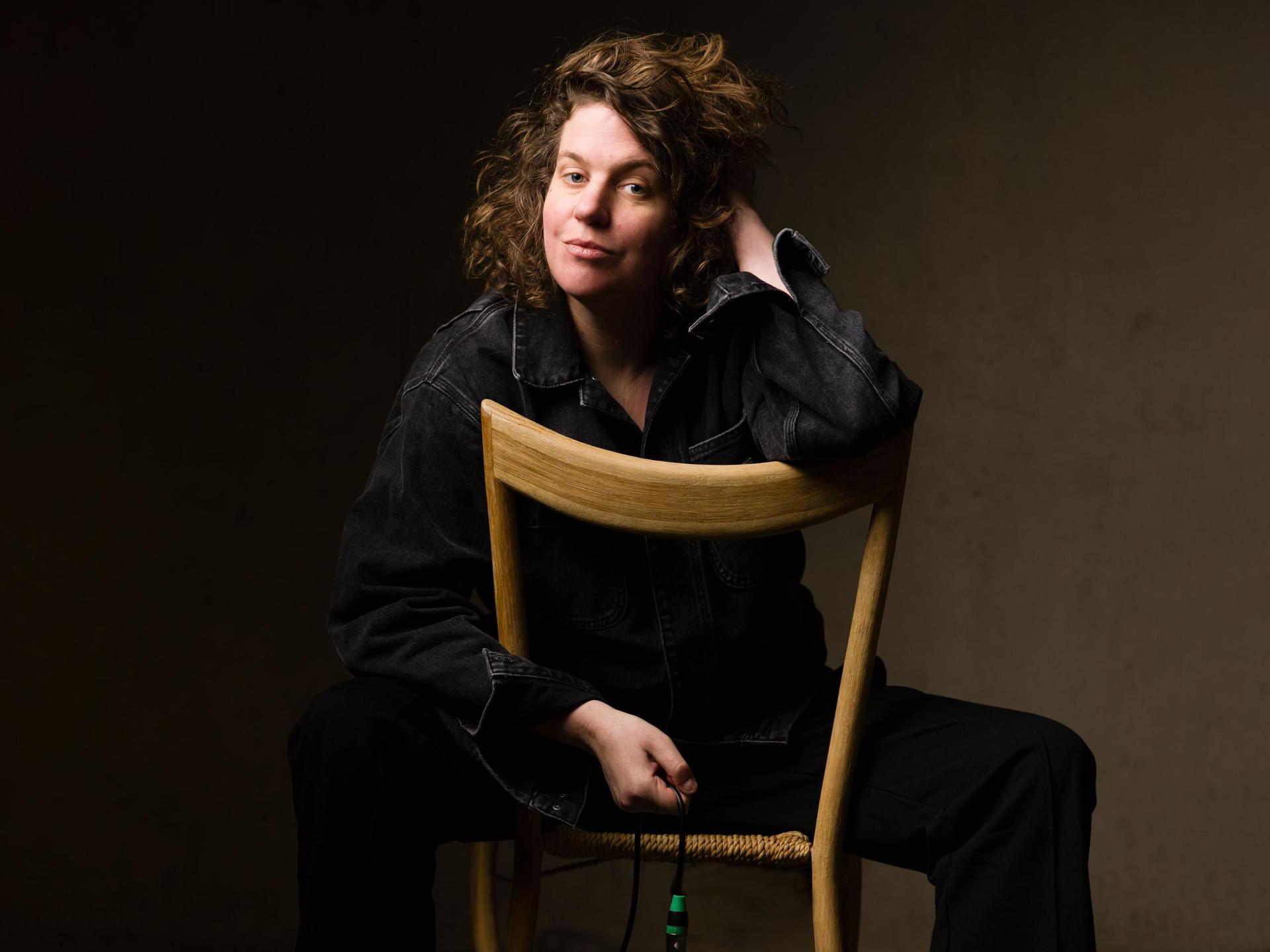 Kim Schuddeboom, Promotiefoto van Kim Schuddeboom achterstevoren op een stoel in zwarte kleding tegen donkere wand