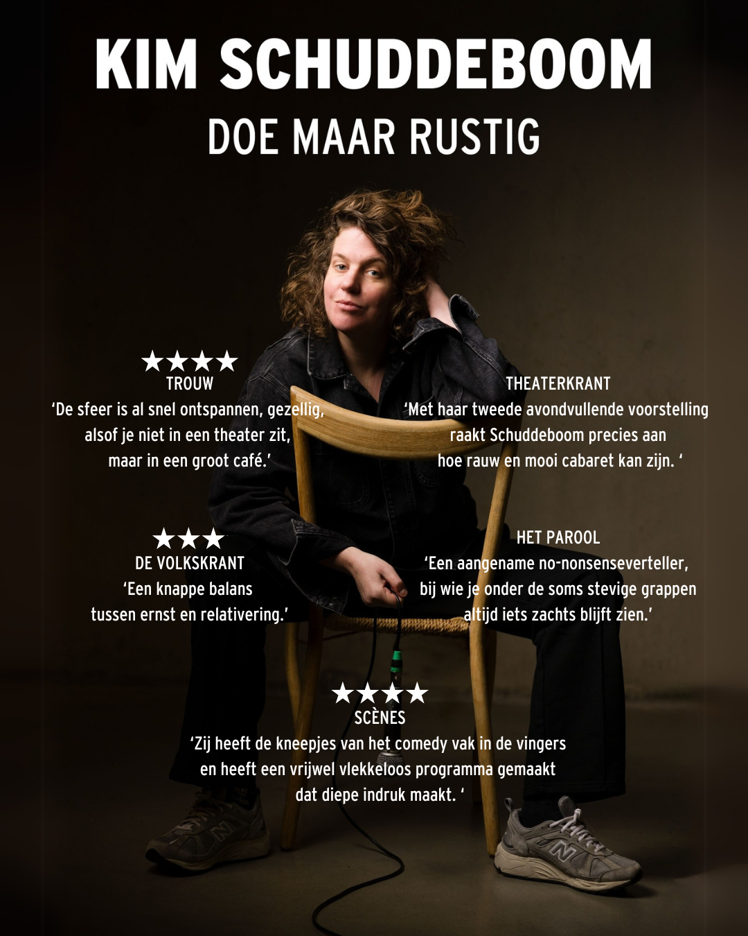 Promotiefoto van Kim Schuddeboom achterstevoren op een stoel in zwarte kleding tegen donkere wand