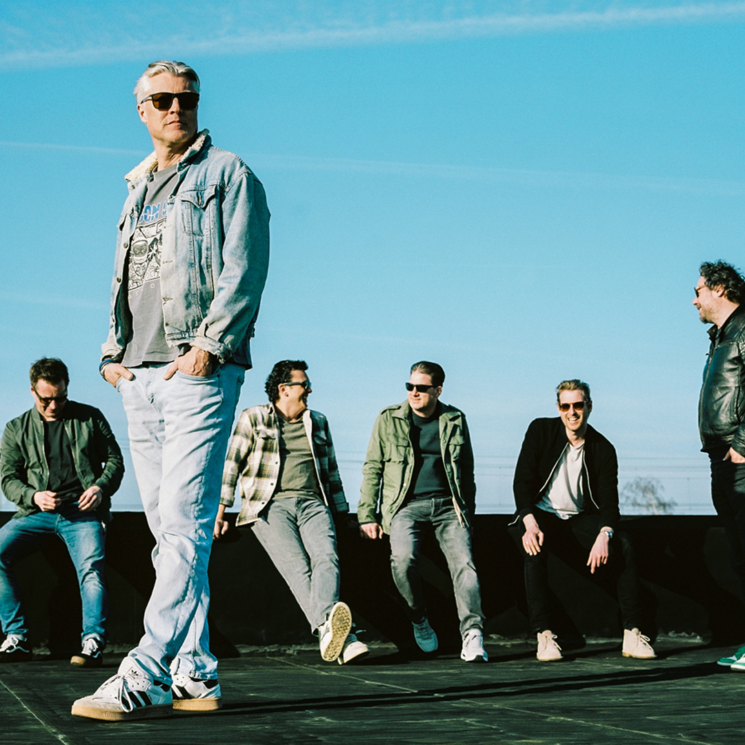 IOS, Promotiefoto van de band IOS - 6 bandleden op een dak tegen een mooie blauwe lucht