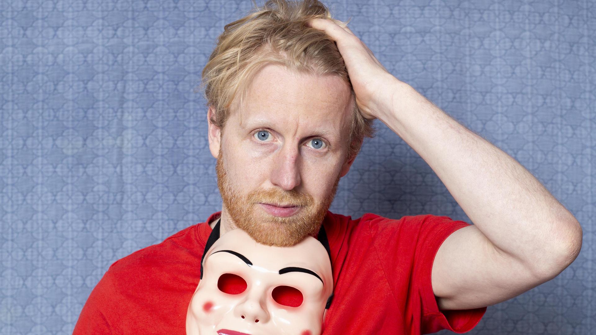 Piet van Eeghen, Promotiefoto van Piet van Eeghen met rood shirt aan, hand in zijn haar en masker om zijn nek