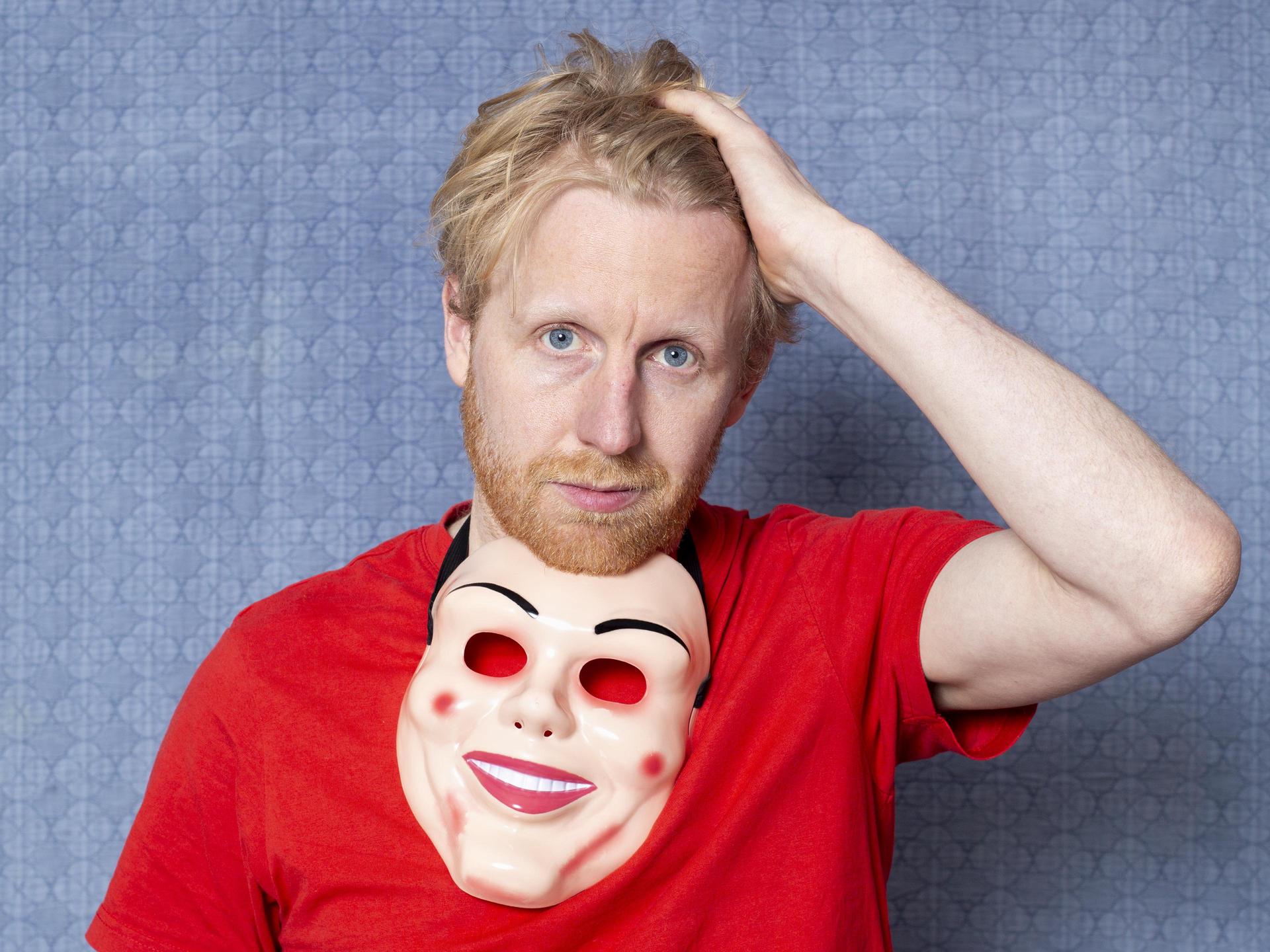 Piet van Eeghen, Promotiefoto van Piet van Eeghen met rood shirt aan, hand in zijn haar en masker om zijn nek