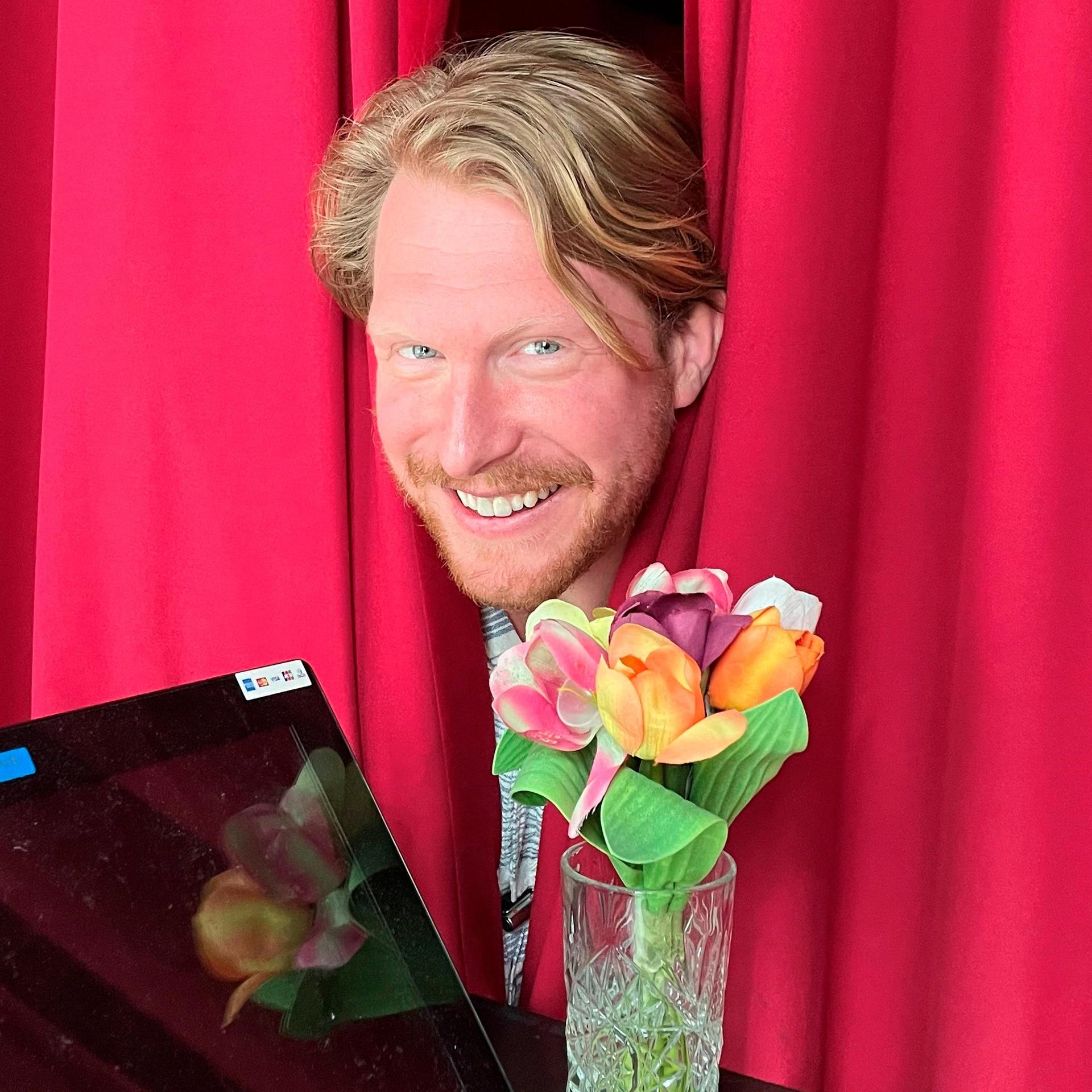 Promotiefoto van Kor Hoebe - zijn hoofd tussen de rode gordijnen met zijn piano op de voorgrond