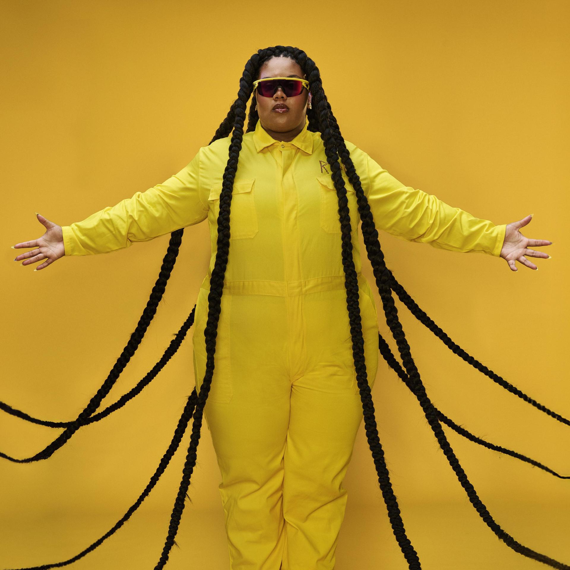 ROF DAAIMUND, Promotiefoto van Isabelle Kafando inmiddels bekend als ROF DAAIMUND in geel pak met lange vlechten