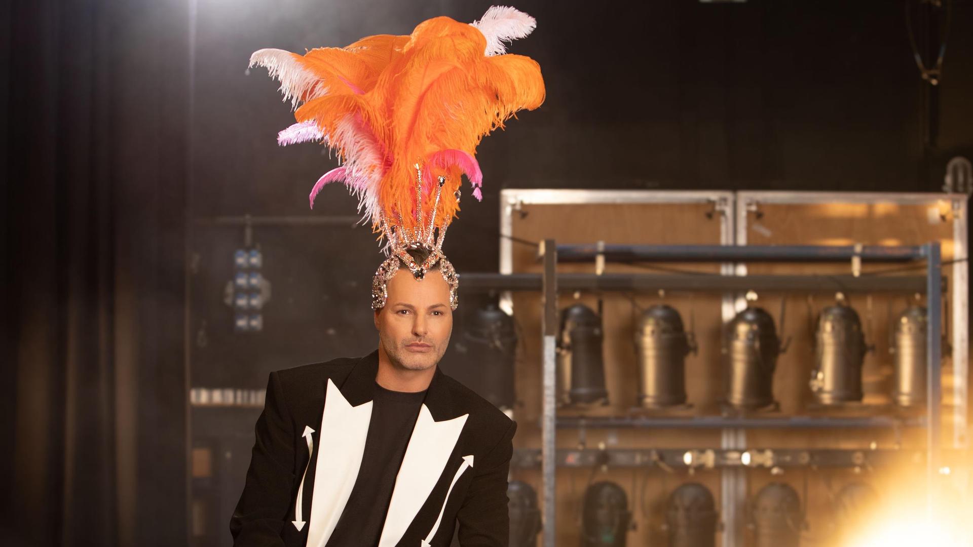 Fred van Leer, Promotiefoto van Fred van Leer zittend op een stoel met een oranje grote verentoog op zijn hoofd