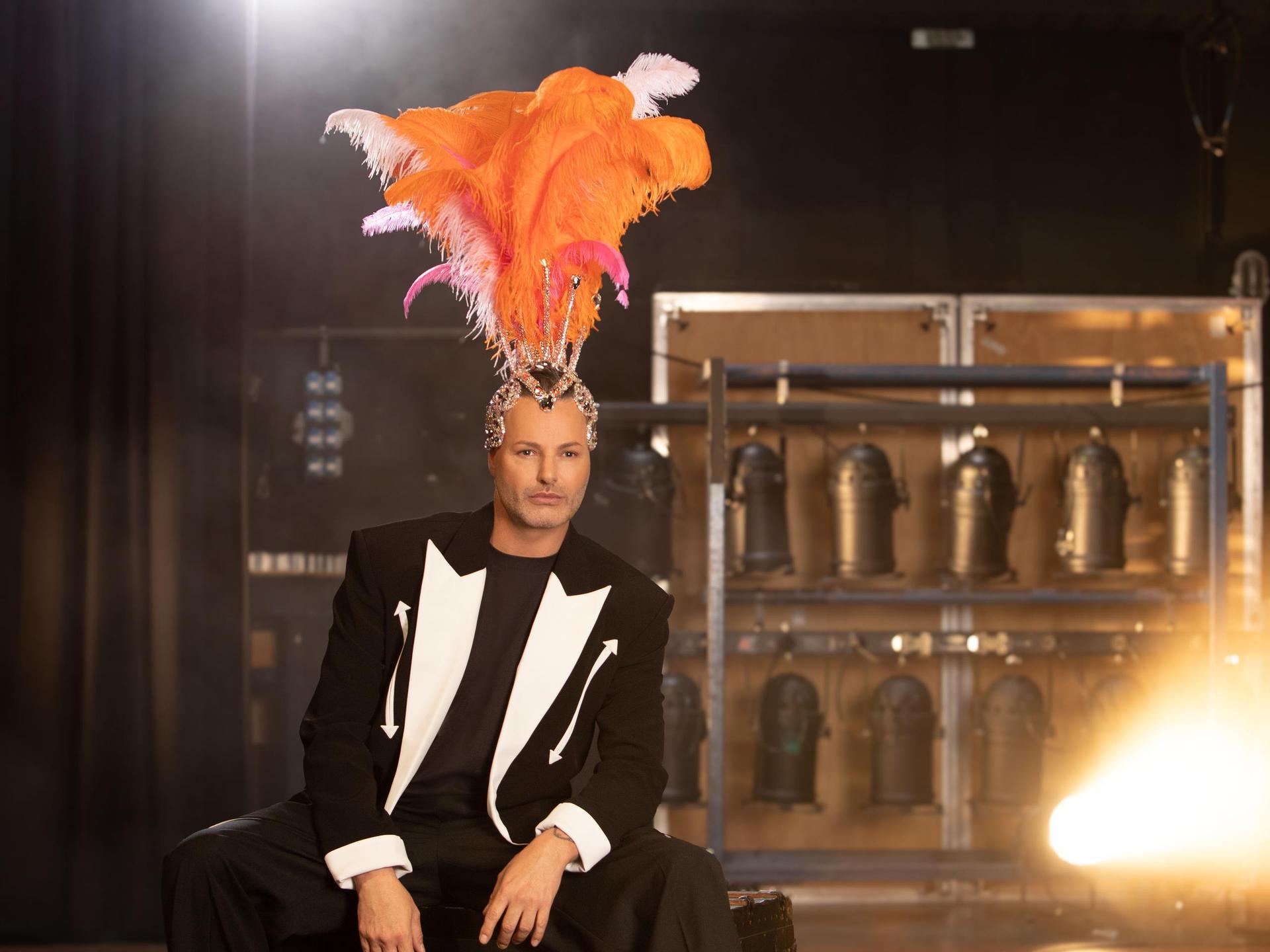 Fred van Leer, Promotiefoto van Fred van Leer zittend op een stoel met een oranje grote verentoog op zijn hoofd