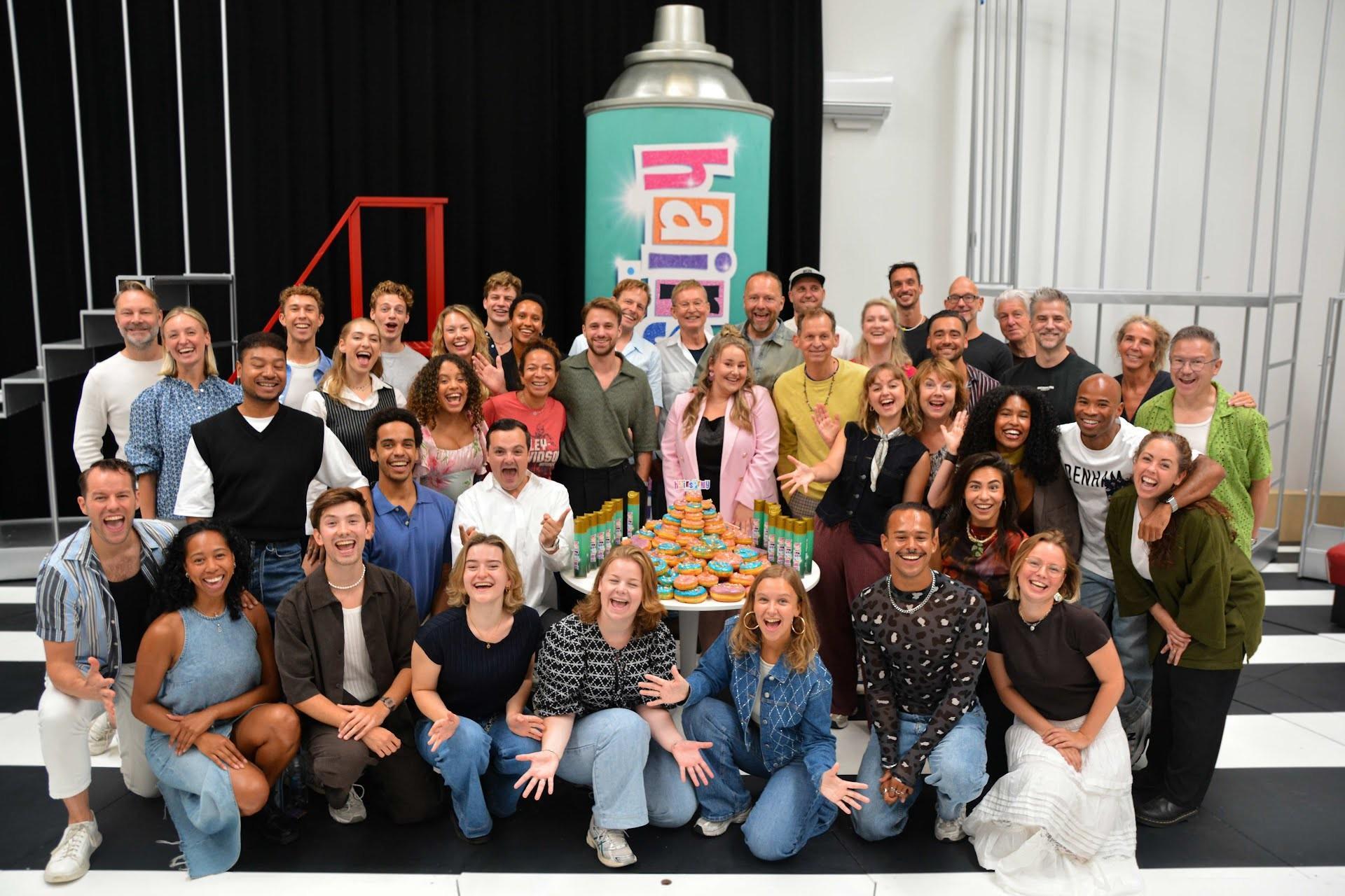 Groepsfoto cast bij de start repities Hairspray met donuttaart.