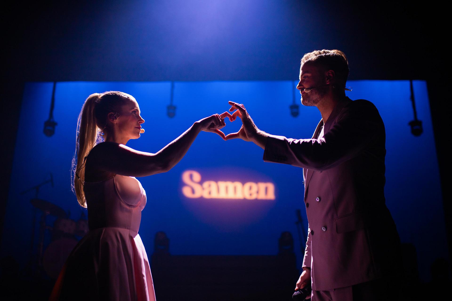 scènefoto Jim en Bettina op het podium, vormen met handen een hartje samen