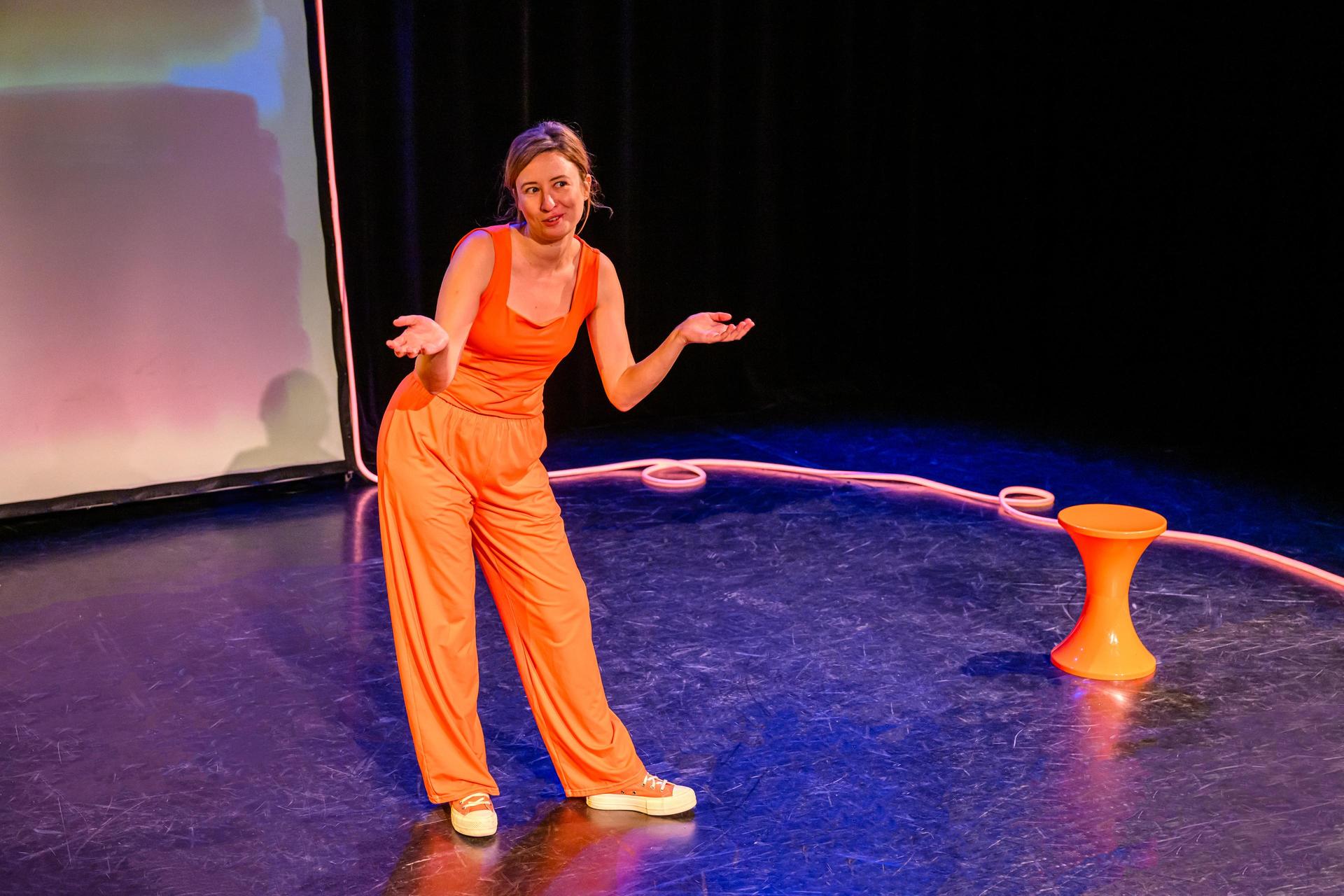 scènefoto met Anne Neuteboom in oranje outfit