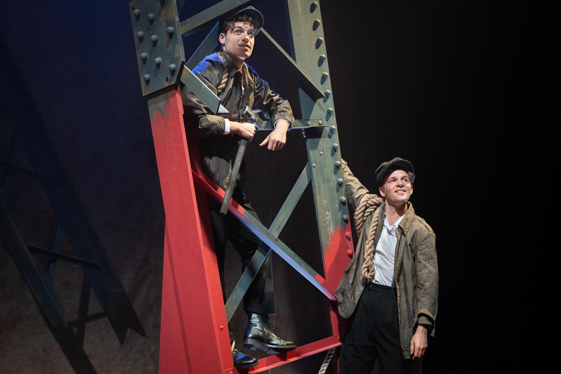 scènefoto musical Eiffel: 2 mannen hangend in poot van de Eiffeltoren