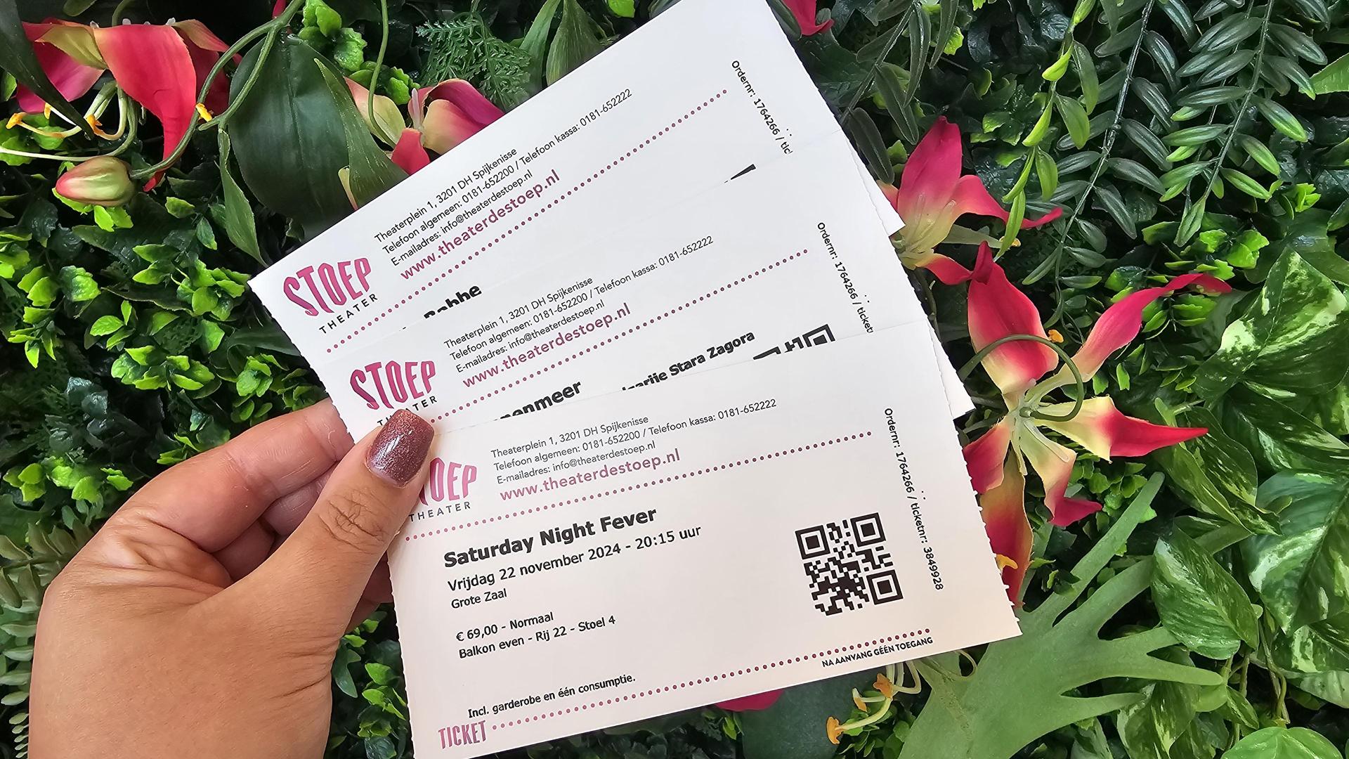 Kaartverkoop, Foto van enkele tickets van Theater de Stoep in een hand vastgehouden tegen groene plantenachterwand