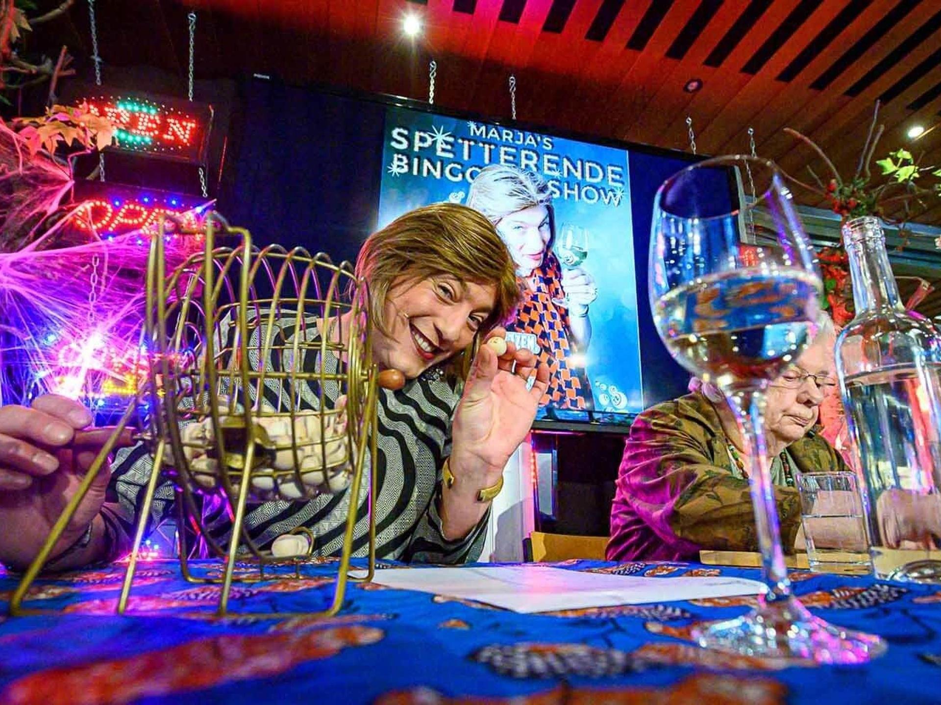 Marja's Spetterende Bingo Show, Foto van Marja van Katendrecht achter Bingomolentje aan tafel met bezoeker die bingo speelt