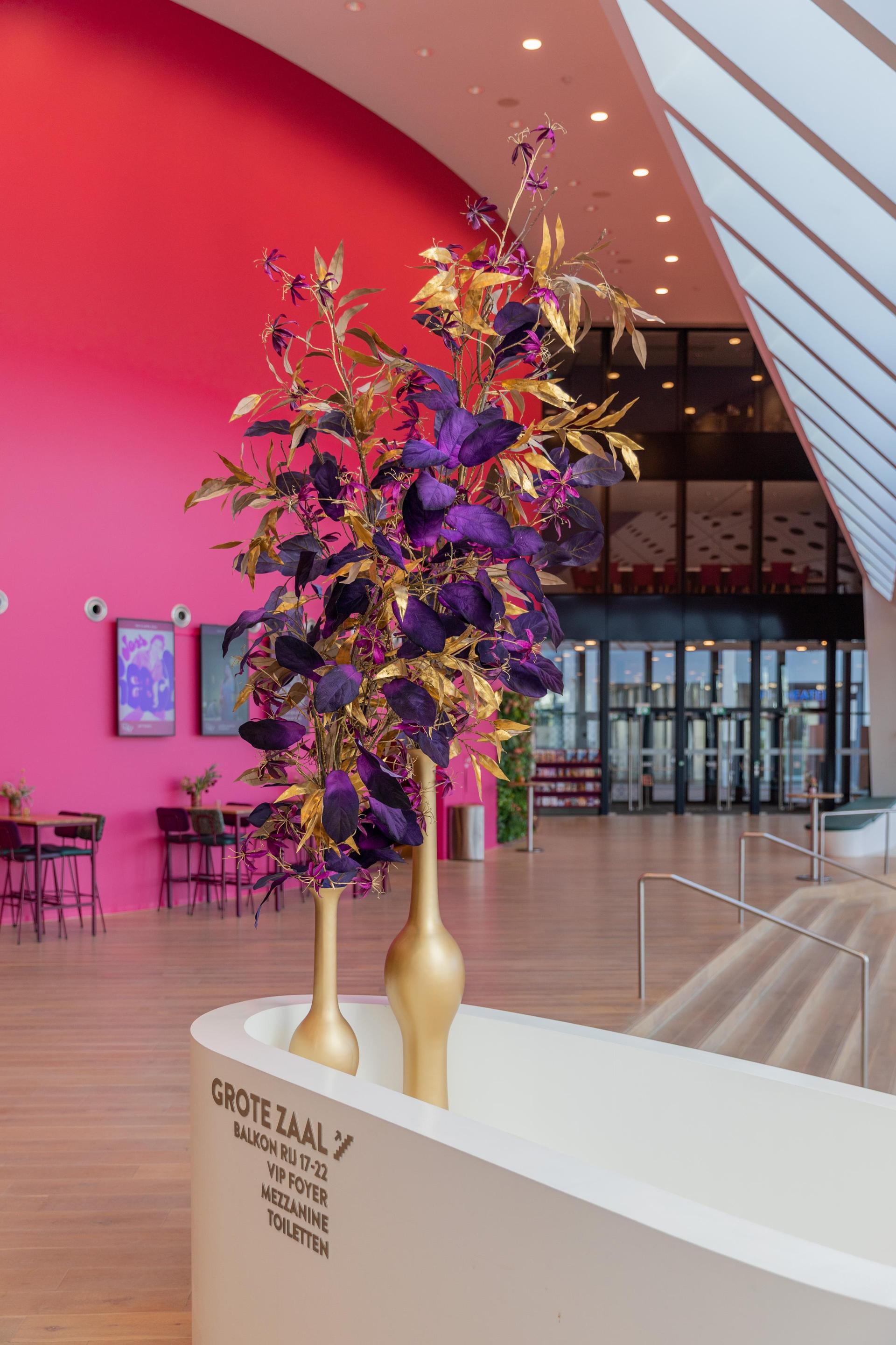 Foto van de foyer van Theater de Stoep bij daglicht gezien vanachter de vaas met bloemen bij de bar