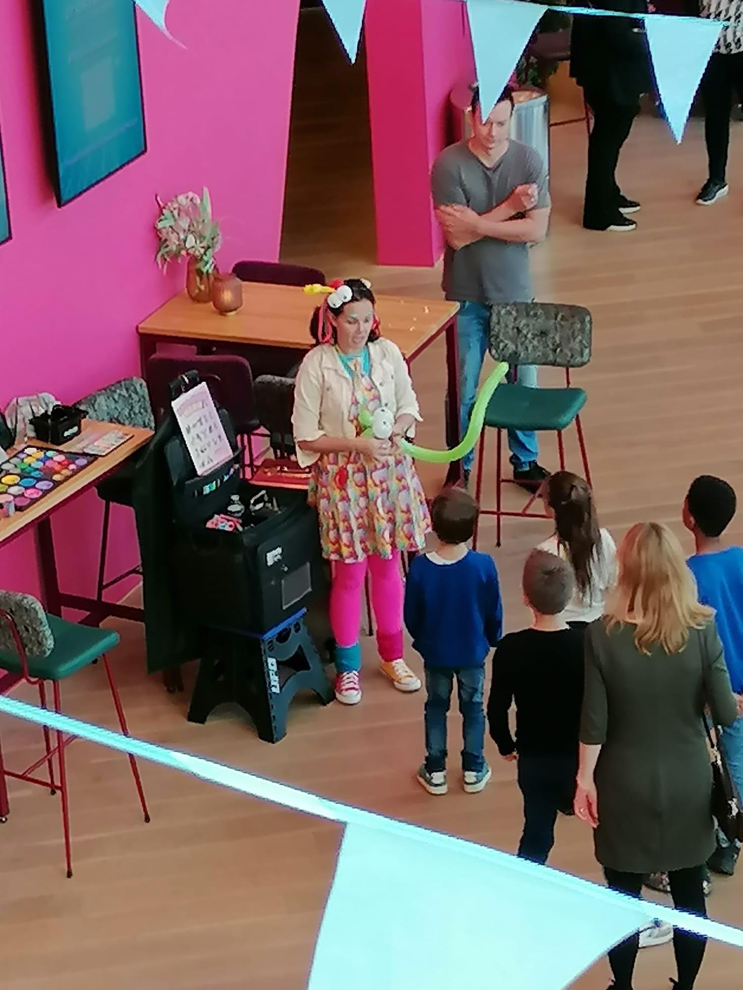 Foto van  Clown Kim tijdens de eerste Stoep Kids Dag met spelende kindjes in de foyer van De Stoep