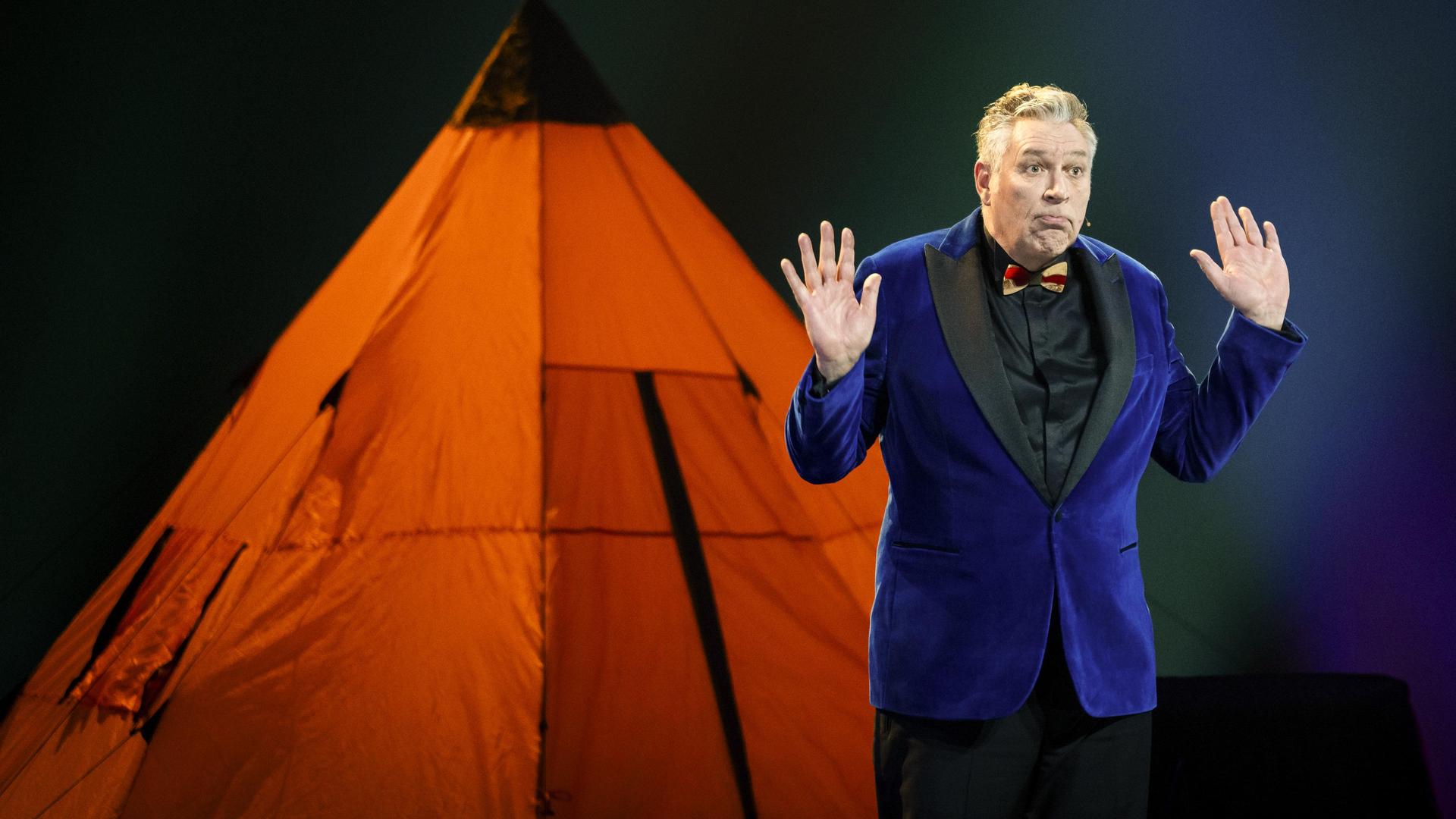Sjaak Bral, Foto van Sjaak Bral voor een oranje tent op het podium
