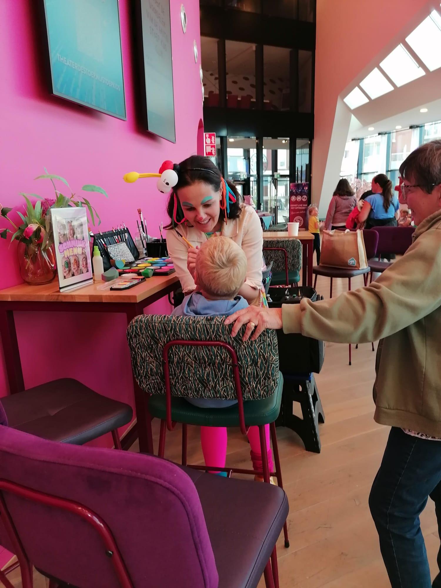 Foto van Clown Kim die een kindje schminkt in de foyer van Theater de Stoep