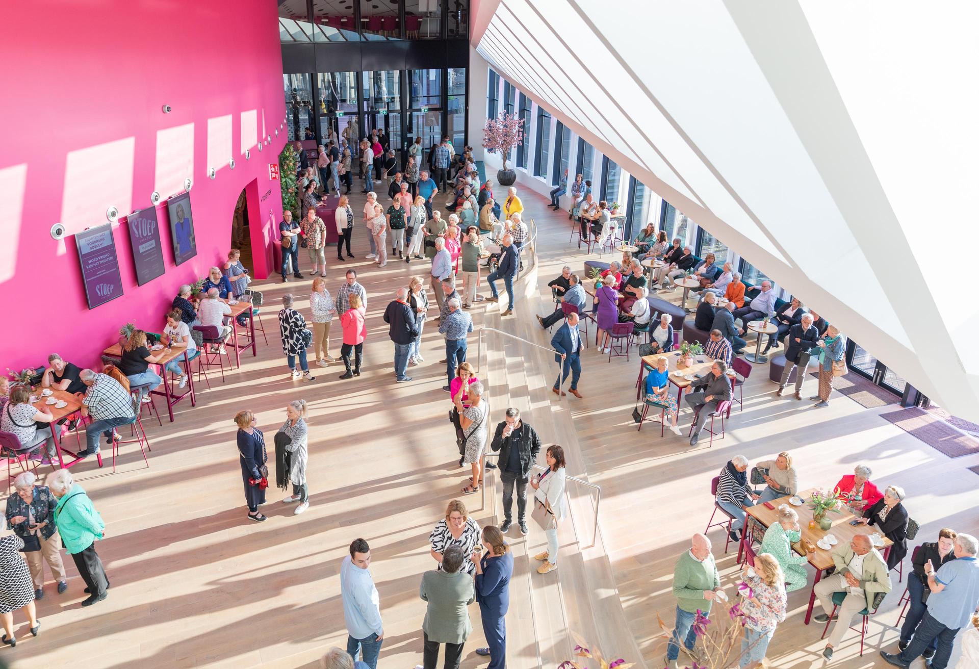 Foto van de foyer van Theater de Stoep met bezoekers bij daglicht genomen vanaf de bovenfoyer