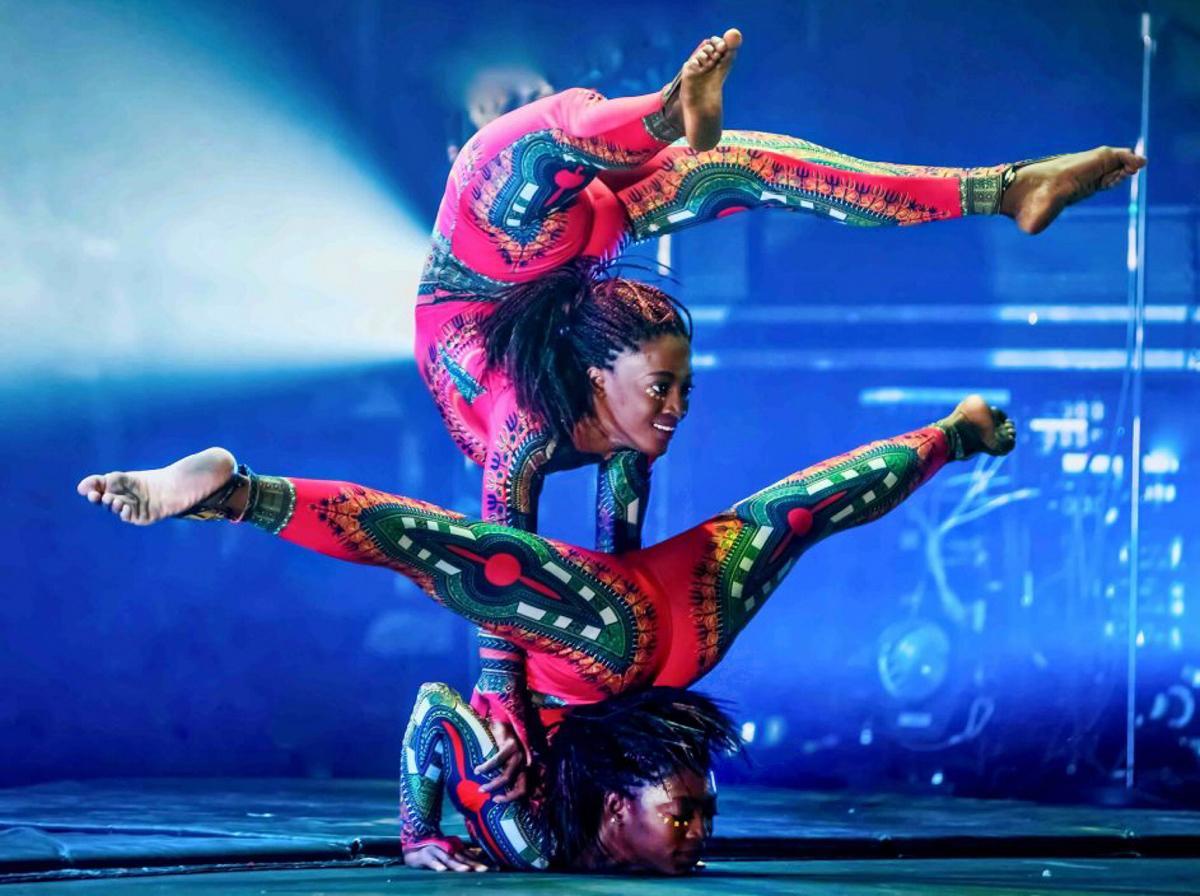 scènefoto van 2 lenige acrobates die boven elkaar op hun handen staan