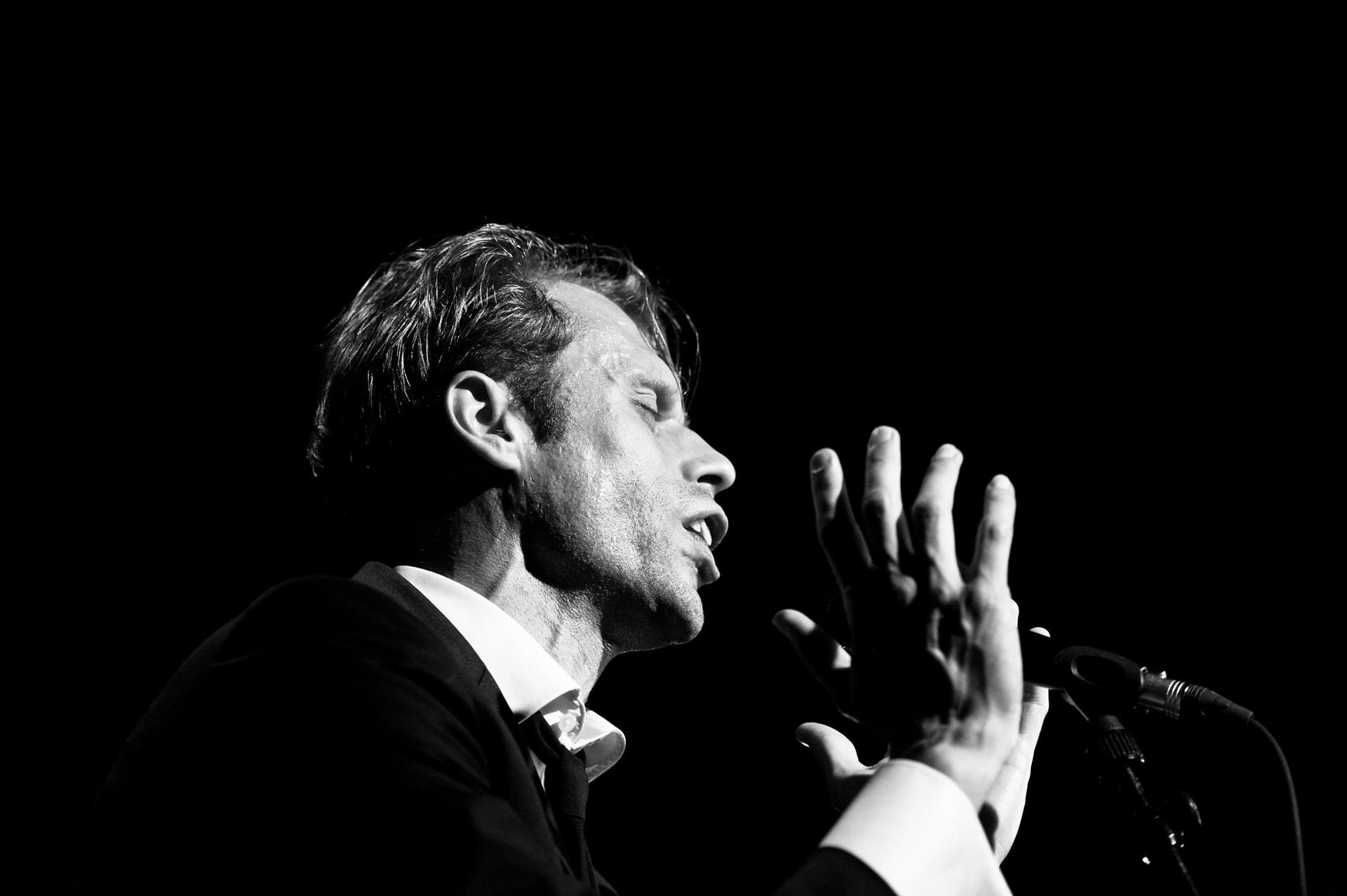 Foto in zwart-wit van Filip Jordens zingend op het podium
