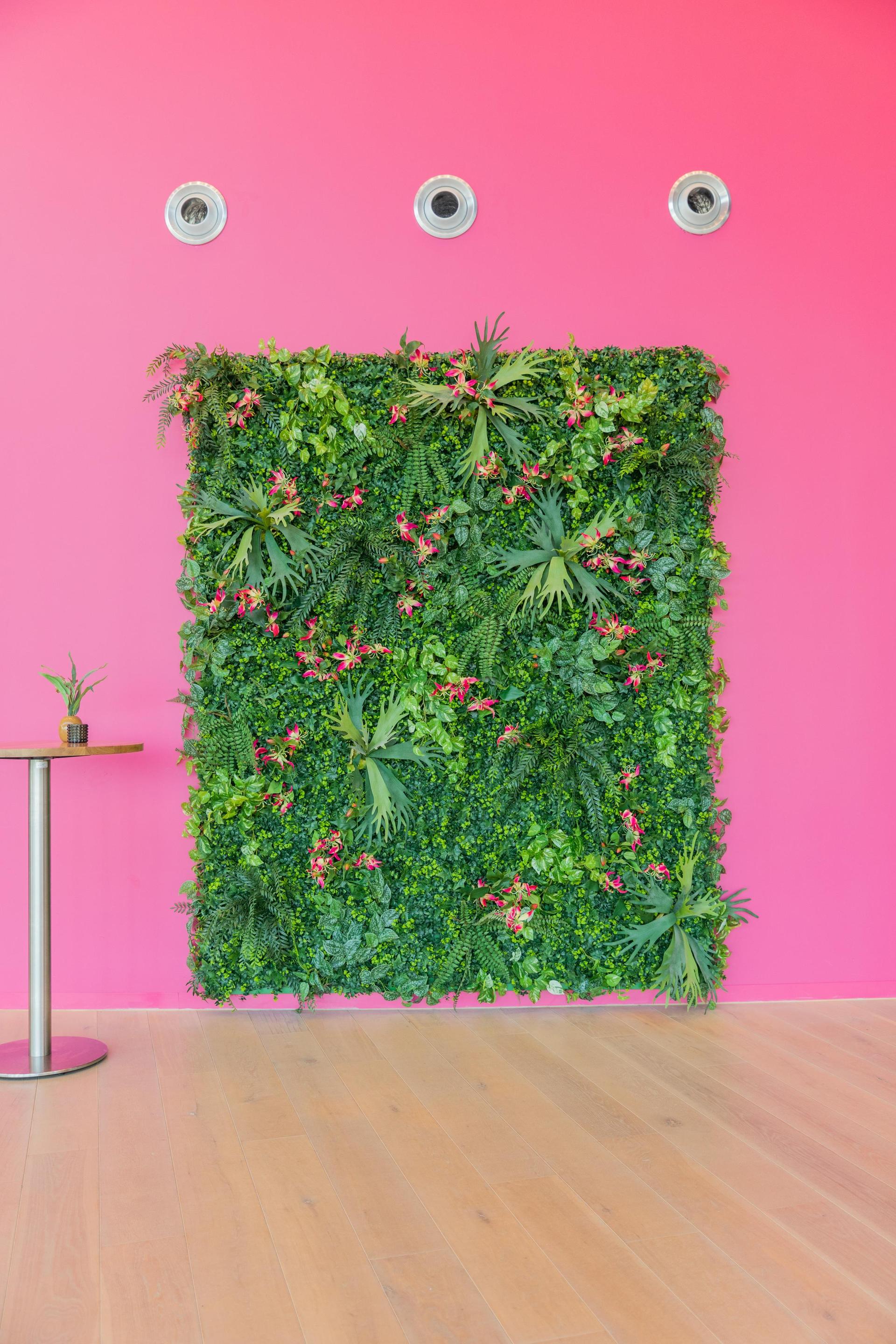 Foto van de groene wand met roze bloemetjes in de foyer bij daglicht