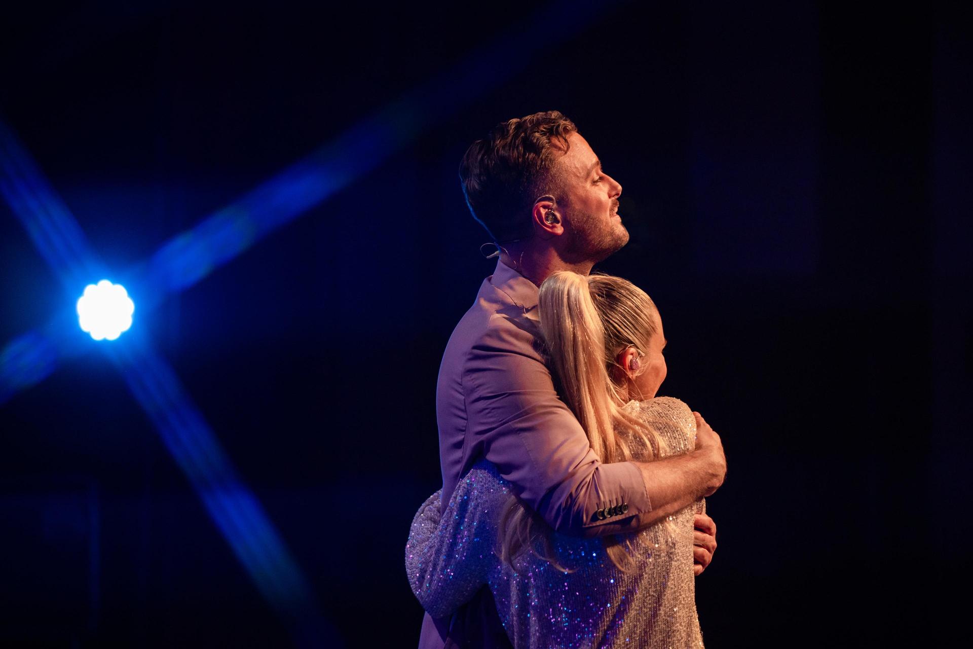 scènefoto Jim en Bettina op het podium, elkaar omarmend